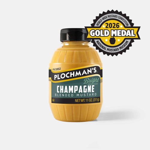 A bottle of Plochman's Champagne Blended Mustard with a black cap, featuring a gold 2026 Gold Medal badge from the Worldwide Mustard Competition from the Mustard Museum.